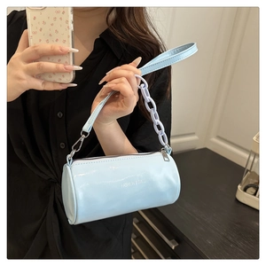 Détail du sac cylindrique bleu clair avec chaîne violette et logo fashion imprimé