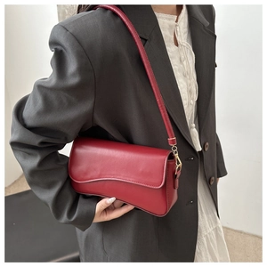 Detalle de un bolso de hombro en cuero mate rojo combinado con una chaqueta gris