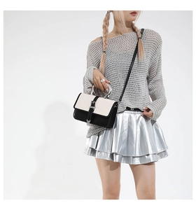 Detail of minimalist black and white crossbody bag with silver ring handle and metal clasp