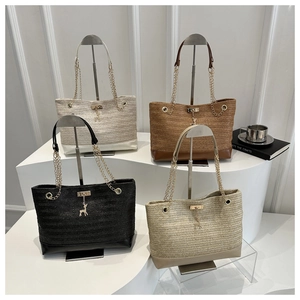 Detail of straw woven tote bags with gold chain straps and metal deer charms in four colors