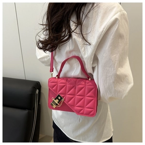 Detail of rose pink quilted crossbody bag with gold hardware worn by a model