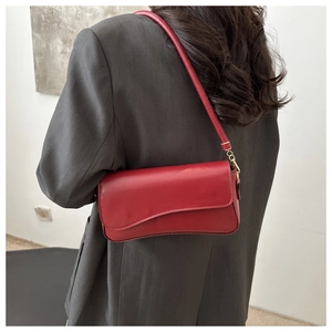Detalle del bolso rojo de cuero con solapa asimétrica y gancho de metal dorado