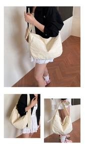 Detail of cream-colored crescent bag showing pleated fabric texture and wide strap