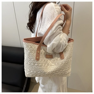 Detail of hand-woven straw tote with pink faux leather straps and golden rivet accents