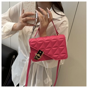 Detail of rose red quilted crossbody bag with golden lock and triangular stitching pattern