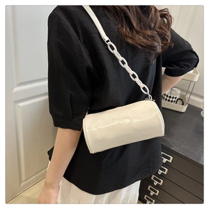 Gros plan du sac cylindrique blanc en cuir PU avec grosse chaîne porté à l'épaule