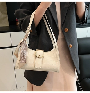 Detail of off-white crocodile pattern shoulder bag with silk scarf and gold buckle