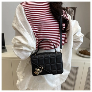 Close-up of black quilted leather crossbody bag with golden lock and chain detail