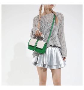 Detail of color-block crossbody bag with green PU flap and elegant silver metal handle