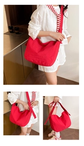 Detailed close-up of a large red pleated canvas tote bag with adjustable wide shoulder strap