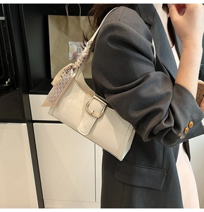 Close-up of white croc-effect baguette bag with gold buckle and chic silk scarf wrap