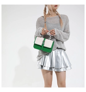 Detail of a chic green and white contrast small square bag with silver metal handle
