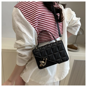 Detail of black quilted shoulder bag with gold square lock and elegant chain strap