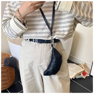 Detailansicht einer schwarzen Croissant-Tasche mit Falten und Riemen am Modell
