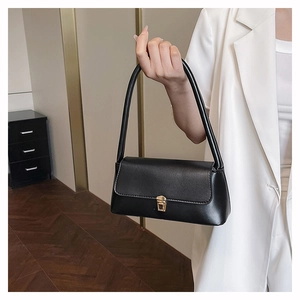 Detail of elegant black underarm bag featuring a refined gold metal buckle and matte finish
