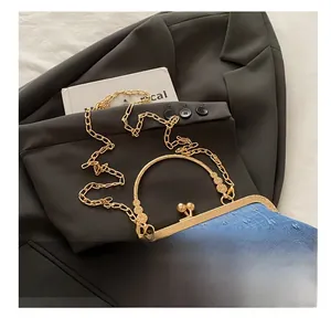 Close-up of blue denim crossbody bag with gold frame, pearl clasp, and metal chain