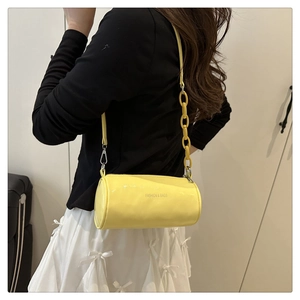 Vue latérale détaillée du sac bandoulière cylindrique jaune avec grande chaîne décorative