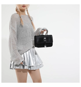 Detail of black leather handbag with sculptural silver handle and buckle strap accents
