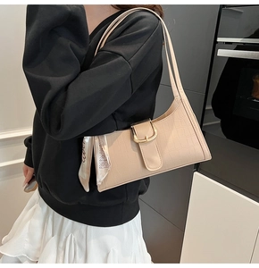 Detail of beige faux crocodile shoulder bag with golden buckle and silk scarf accent