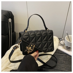 Detailed close-up of black quilted texture with elegant gold hardware lock on bag