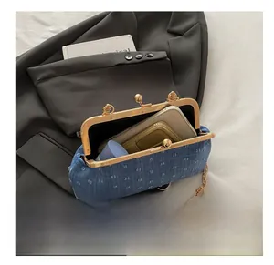 Detail showing internal capacity of blue denim kiss-lock bag with gold chain and textures