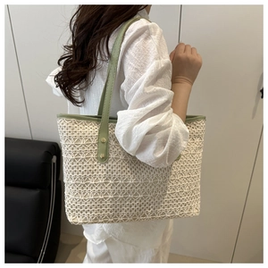 Detail of white woven tote bag featuring light green leather trim and gold rivet hardware