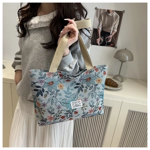 Close-up of floral jacquard tote bag with blue leaf pattern and woven cotton handles