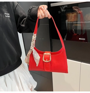 Detail of red crocodile pattern baguette bag with gold buckle and floral scarf handle
