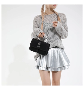 Detailed view of a black Y2K style handbag with silver metal handle on a model