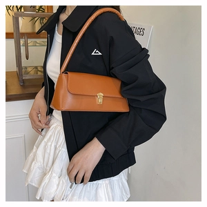 Close-up of caramel brown baguette bag with golden swivel lock and smooth leather texture