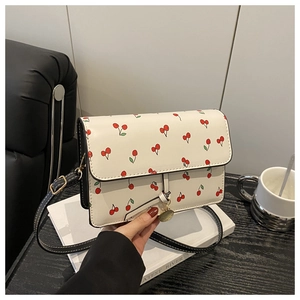 Detailed view of cherry print mini crossbody bag with golden charm and black strap