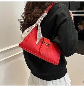 Detail of red crocodile texture baguette bag with silk scarf on the shoulder strap