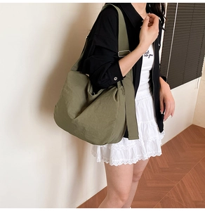 Detail of soft dark green crossbody bag with wide shoulder strap and silver buckle