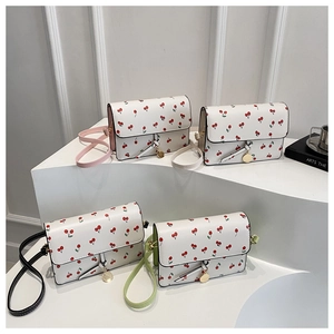 Detailed view of cherry print crossbody bags in pink, white, black, and green straps
