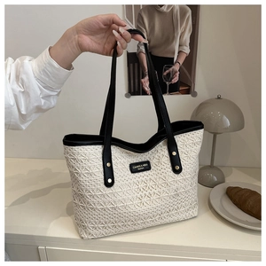 Close-up of geometric lace crochet tote bag with black leather straps and contrast trim