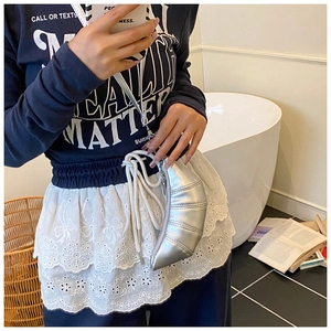 Detailansicht einer silbernen Croissant-Tasche mit Metallfalten und Reißverschluss