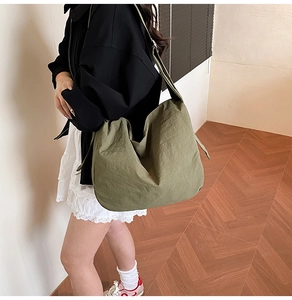 Detail of wide shoulder strap on an olive green nylon tote bag with draped folds