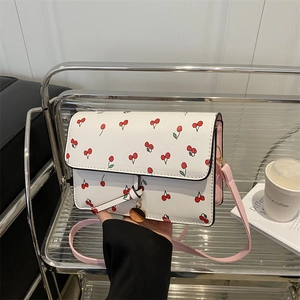 White cherry print crossbody bag with pink strap and golden metal charm for women