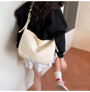 Detail of soft cream tote bag showing the textured pleats and wide adjustable strap