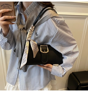 Detail of black crocodile pattern baguette bag with gold buckle and silk scarf handle