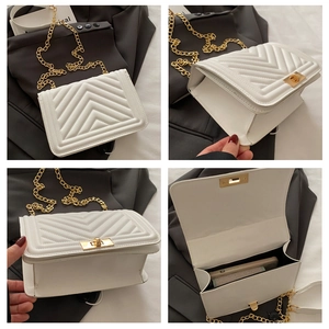 Detail view of white quilted leather bag with V-shaped texture and gold push-lock closure