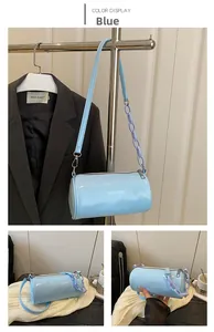 Dettaglio della borsa a cilindro azzurra con testo moda e tracolla a catena viola