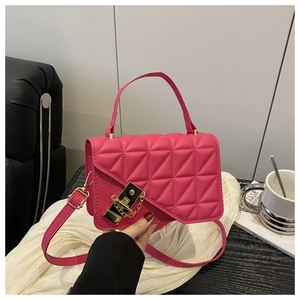 Detail of pink quilted square bag with gold twist lock and chain on silk fabric