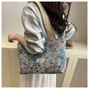 Detailed back view of a large floral canvas tote bag worn by a model in a minimal setting