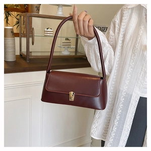 Close-up of vintage dark wine red shoulder bag with golden metallic twist lock closure