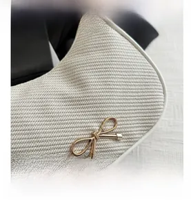 Macro shot of off-white woven crescent bag texture with golden bow buckle detail