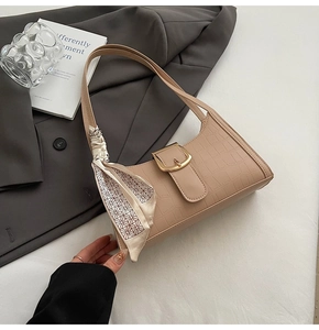 Detail of beige crocodile embossed baguette bag with silk scarf on leather strap