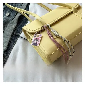 Detailed close-up of yellow baguette bag showing neat stitching and decorative woven pendants