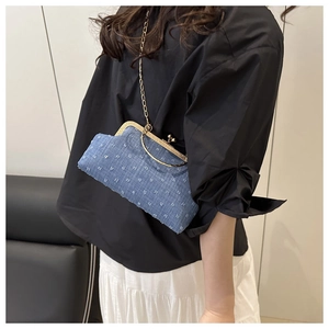 Dettaglio borsa a conchiglia in denim blu con ricami e elegante tracolla dorata