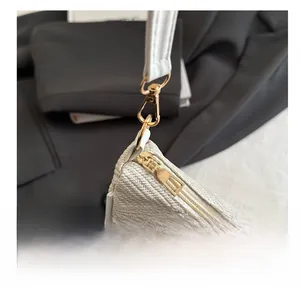 Close-up of cream woven fabric bag with smooth golden zipper and metal hook details